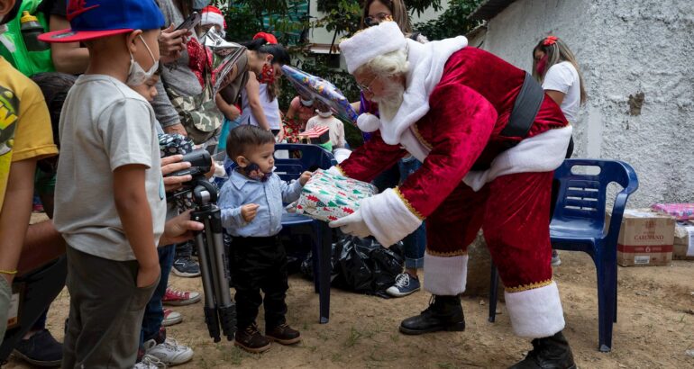 Un hombre vestido de Santa Claus entrega de regalos de "Un Juguete, una buena noticia" hoy, en Caracas (Venezuela). Foto de EFE/ RAYNER PEÑA R.