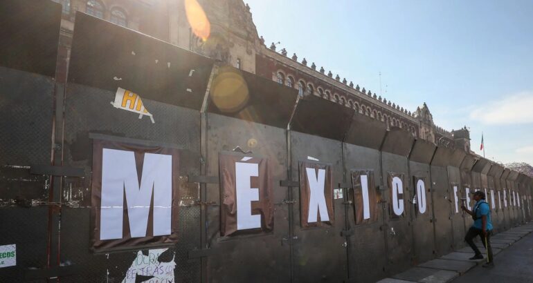 Una persona supervisa la instalación de un cerco de vallas colocado frente al Palacio Nacional, previo a la marcha del 8 de marzo de 2023, en Ciudad de México. Foto de EFE/Isaac Esquivel