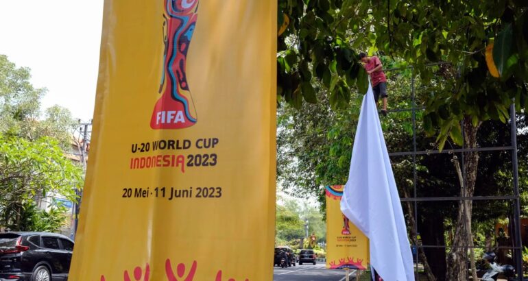 Un trabajador retira una pancarta de la Copa Mundial Sub 20 de la FIFA 2023 en Denpasar, Bali, Indonesia. Foto de EFE/EPA/MADE NAGI