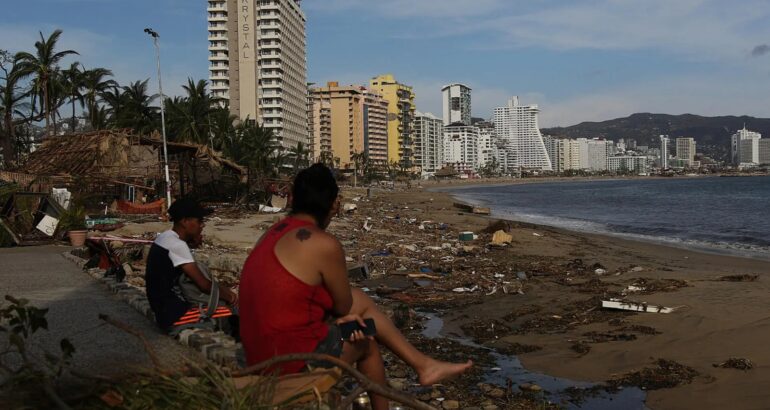 Personas permanecen sentadas junto a los escombros causados por el huracán Otis, en Acapulco, Guerrero. Foto de EFE/José Luis de la Cruz