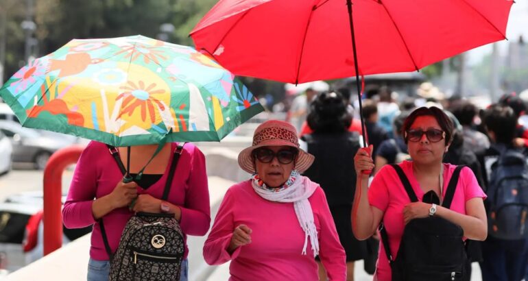 Mujeres sostienen sombrillas para protegerse del sol en la Ciudad de México. Foto de EFE/Mario Guzmán